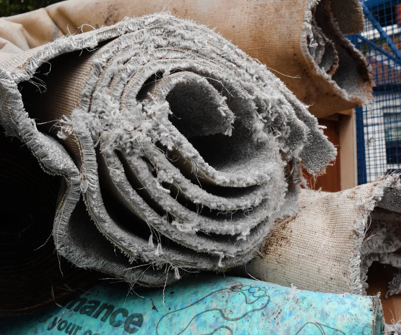 old and dirty rolls of carpet and underlay stacked on top of eachother