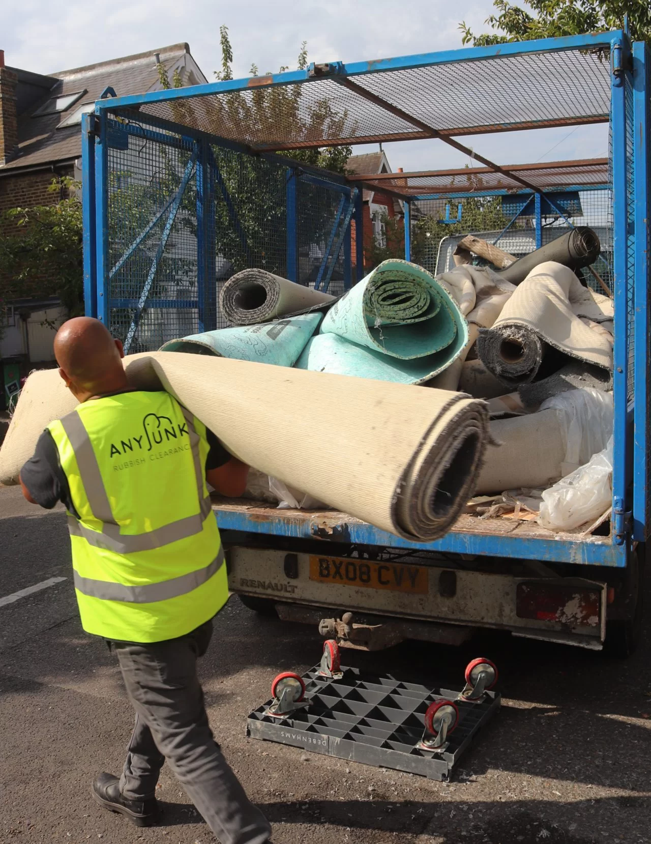 anyjunk waste contractor carrying roll of carpet to van to dispose of