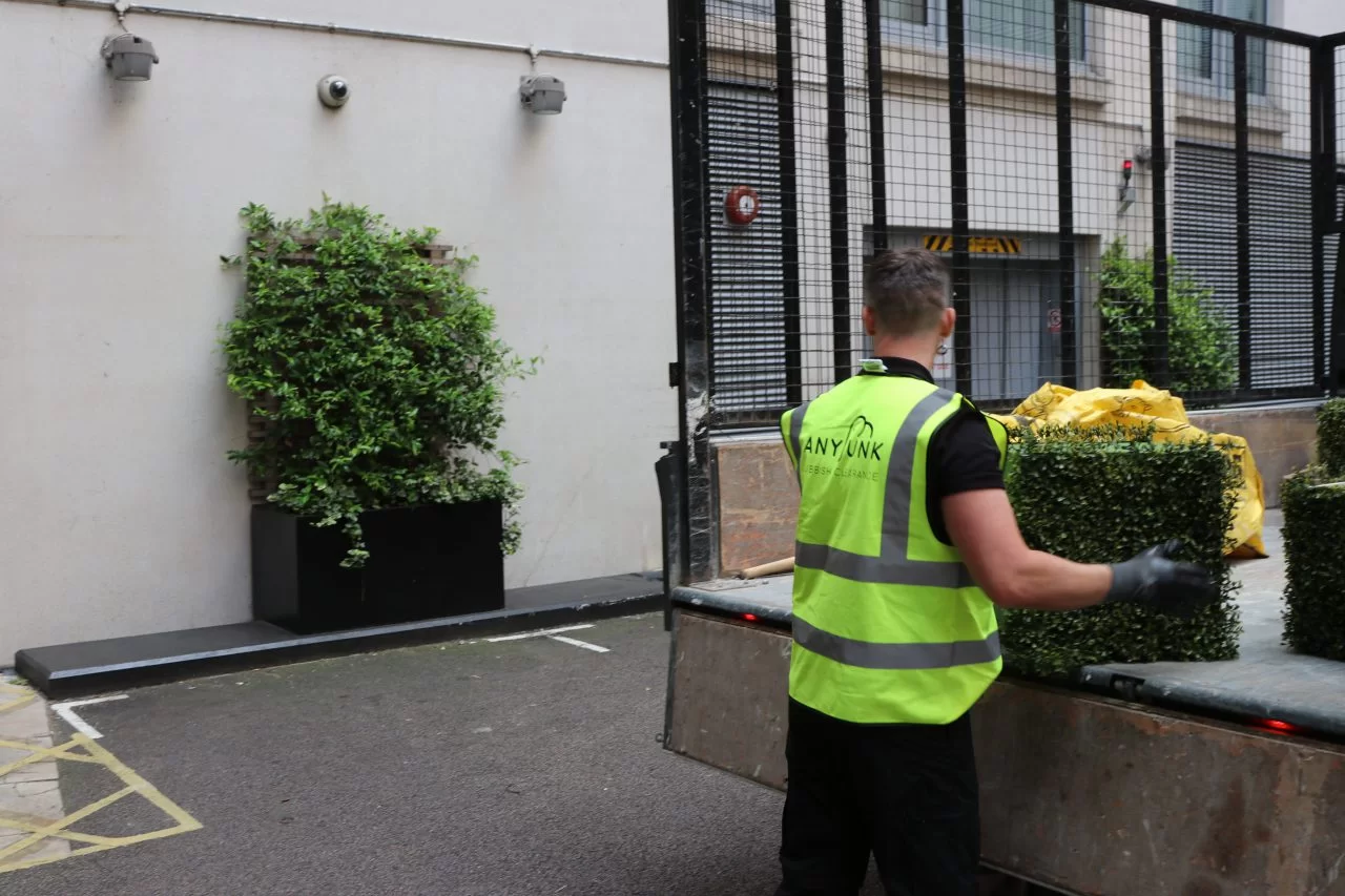 anyjunk waste removal company clearing garden waste refuse into back of truck