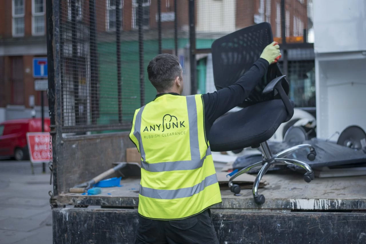 anyjunk waste removal company loading old office furniture into van for disposal and recycling