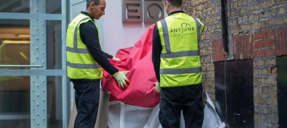 two anyjunkwaste contractor crew members collecting pink skip bag for disposal